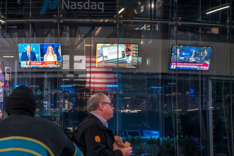 Un hombre camina frente a unos monitores de televisión, encendidos con reportes sobre las elecciones presidenciales, este miércoles en el edificio de Nasdaq en Nueva York (EE.UU.). EFE/Ángel Colmenares 01061124